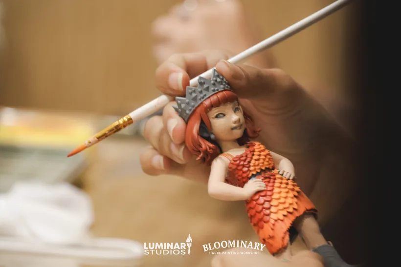 Finished figure held beside a paintbrush