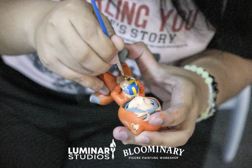 Close-up of a figure being painted orange